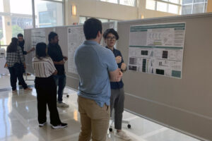Students presenting posters in a large open room