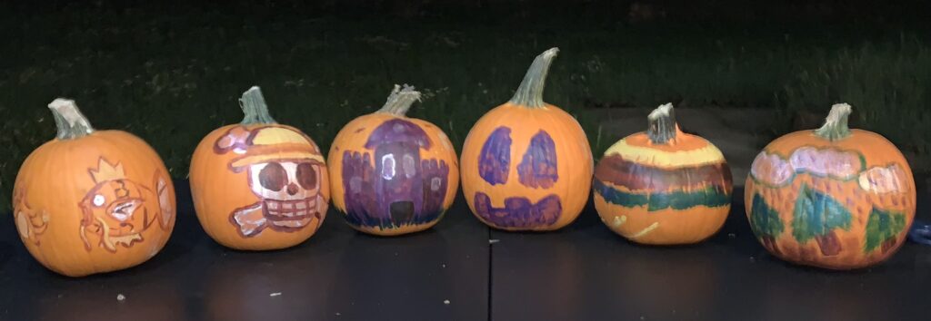 six pumpkins painted and sitting in a row