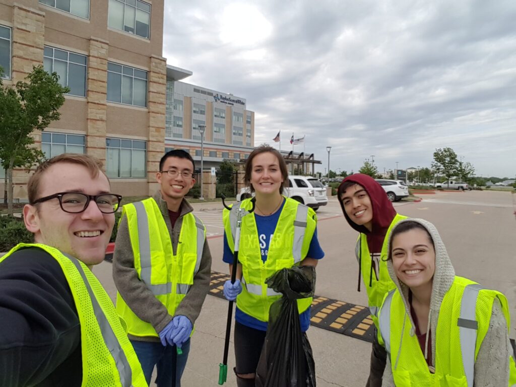Students wearing high-visibility vests picking up trash for The Big Event