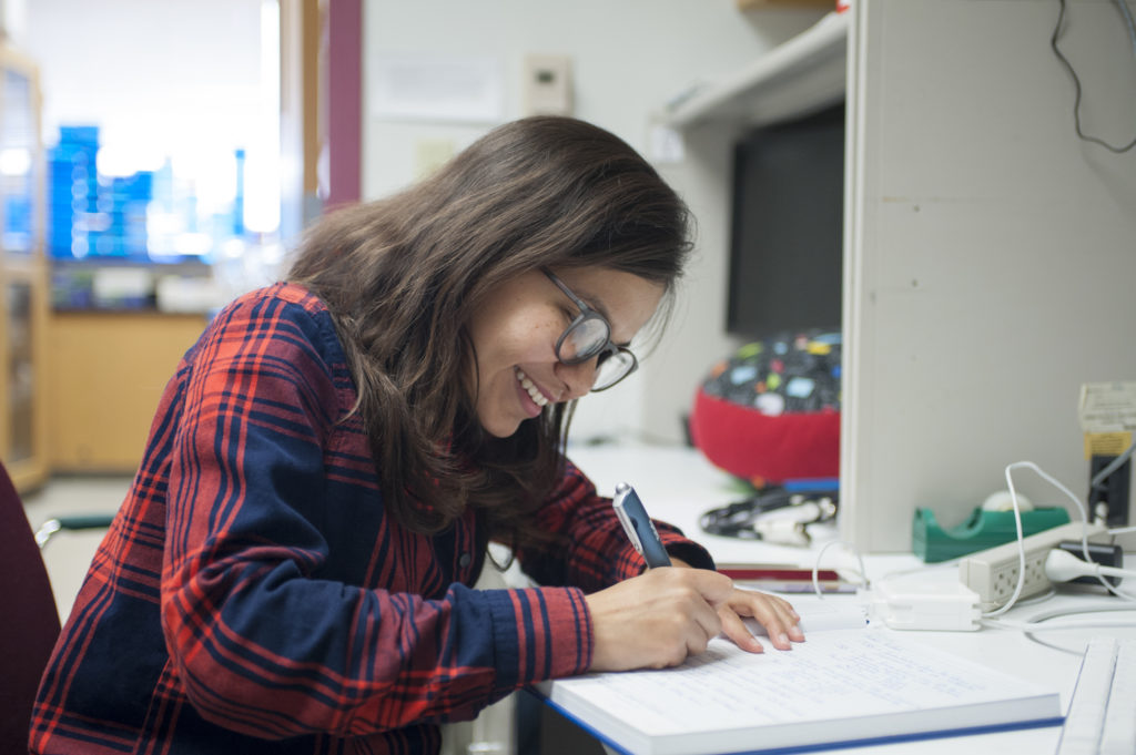 woman smiling and writing in a notebook