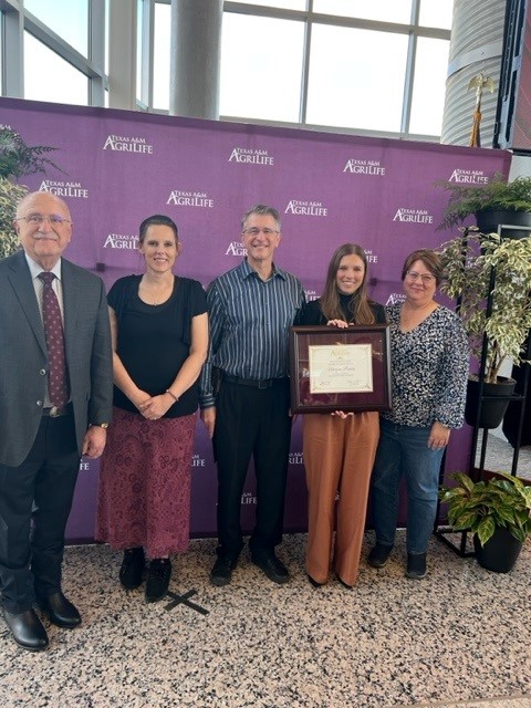 Morgan Powers holding award with group of people