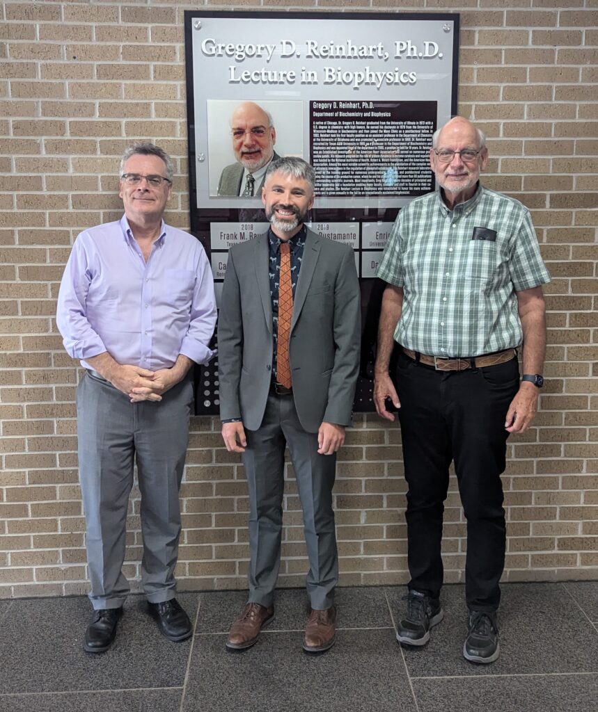 Three men standing together and smiling.